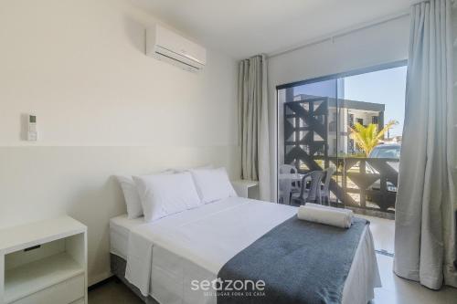 a white bedroom with a bed and a balcony at Aptos em condo. com churrasq. e piscina na melhor localização de Porto Seguro – DVBs in Porto Seguro