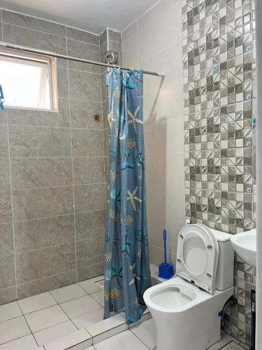 a bathroom with a toilet and a shower curtain at Hidden gem-Nyali Vale Residence in Mombasa