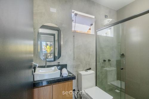 a bathroom with a sink and a toilet and a mirror at Aptos em condo. com churrasq. e piscina na melhor localização de Arraial d'Ajuda – DVBs in Coroa Vermelha