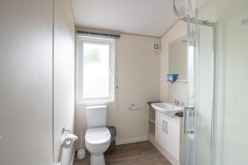 a bathroom with a toilet and a sink and a window at Golden Sands Holiday Park in Kinmel Bay
