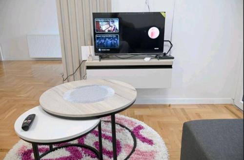a living room with a table and a tv at Apartmani Slavica in Požega