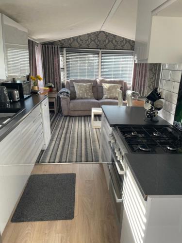 a kitchen and a living room with a couch at Tingdene caravan park in Gunton