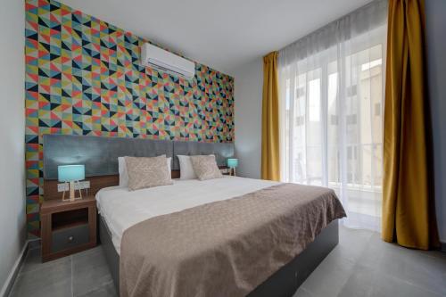 a bedroom with a bed and a colorful wall at Dar One - Self catering & self check in apartments by Tritoni Hotels in Il-Gżira