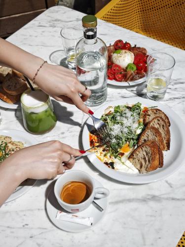 Ein Tisch voller Teller mit Essen und eine Person, die einen Salat schneidet. in der Unterkunft Apartament Różowy Jeleń in Gliwice