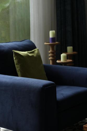 a blue couch with a green pillow in a living room at Casa Calma - 2BHK Luxury Villa with Private Pool by evaddo in Siolim