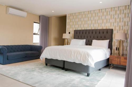 a bedroom with a large bed and a blue couch at Simphiwe Guesthouse in Manzini