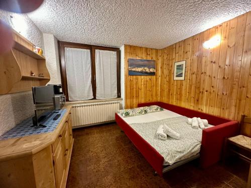 a bedroom with a bed and a tv in it at Dimaro-Folgarida Apartment in Monclassico