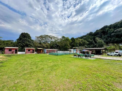 eine große Rasenfläche mit Spielplatz und Gebäuden in der Unterkunft Ohana in Peruíbe