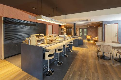 una cocina con una barra larga con sillas y mesas en Sure Hotel by Best Western Dole, en Dole