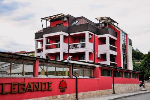 a red and white building on the side of a street at Elegance Spa Hotel in Ognyanovo