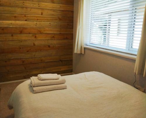 - une chambre avec 2 serviettes sur un lit et une fenêtre dans l'établissement White Cliff Rest, à Seaford