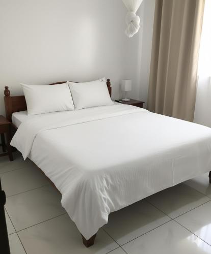 a large white bed with white sheets and pillows at Jambo Guest House in Taba