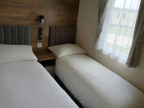 two beds in a small room with a window at Lakeland Leisure Park - Holiday Accommodation 20349 in Flookburgh