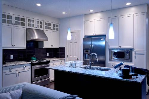 Una cocina con gabinetes blancos, un fregadero y una estufa. en Evanston House, en Calgary