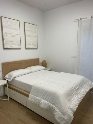 a white bedroom with a bed and a window at Casa ARANAL in Málaga
