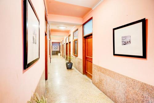 un couloir d'un immeuble de bureaux avec des tableaux aux murs dans l'établissement Hotel O The Swarnim, à Noida