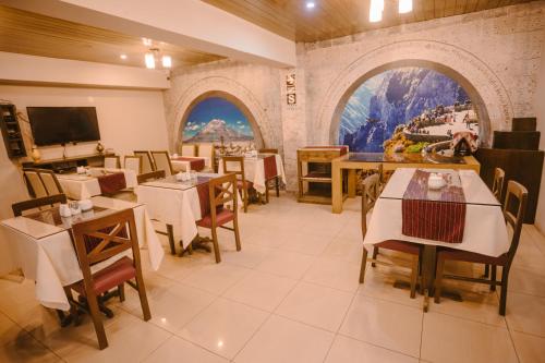 a restaurant with tables and chairs and two arched windows at Villa Sillar in Arequipa