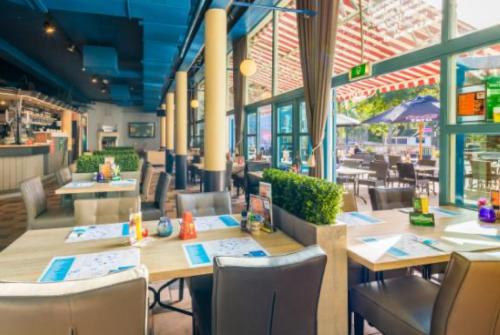 a restaurant with wooden tables and chairs and windows at Vakantiepark Kijkduin - 870 in The Hague