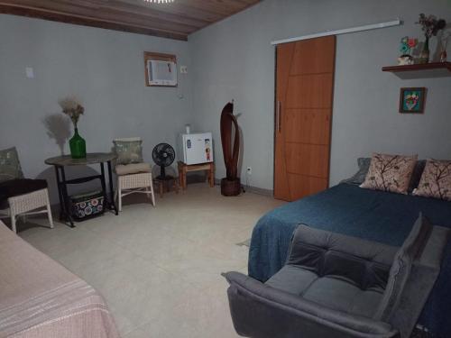 Un dormitorio con una cama, una silla y una mesa. en Sítio Doce Mel, en Saquarema