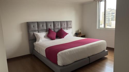 una camera da letto con un grande letto con cuscini rossi e viola di Hotel Bogota DC a Bogotá