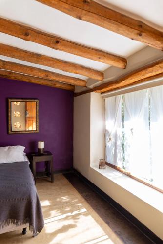 a bedroom with purple walls and a window at Al Sereno Hotel Spa in Tilcara