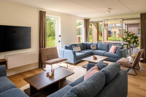 a living room with blue couches and a flat screen tv at Dormio Resort De Hondsrug in Gasselte