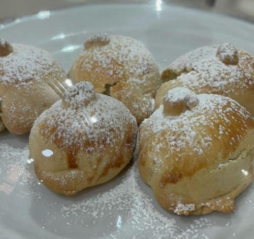 four donuts covered in powdered sugar on a plate at Mg Palace Hotel Costa del Sole in Vaccarizzo - Delfino