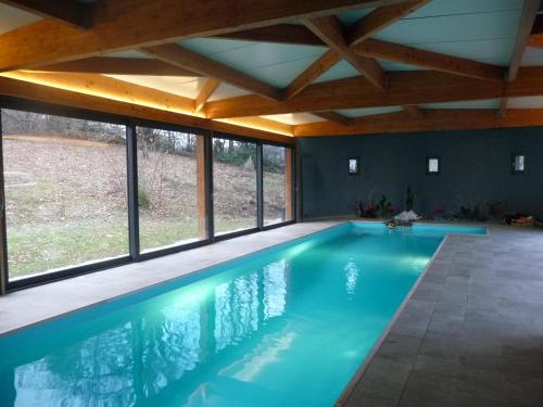 een zwembad in een huis met ramen bij Les Grands-Parents in Corancy