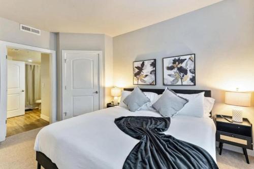 a bedroom with a white bed with a black blanket on it at 1min Delta - Salt Palace - King Bed - Gym - Parking in Salt Lake City