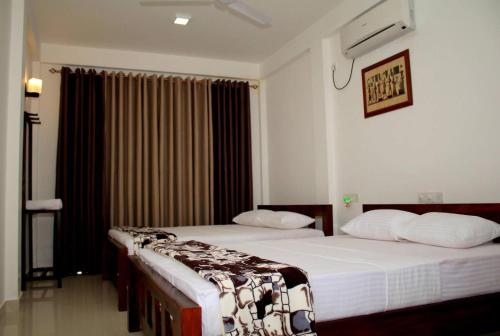 two beds in a hotel room with a window at Seasons Villa Sigiriya, Sri Lanka in Dambulla
