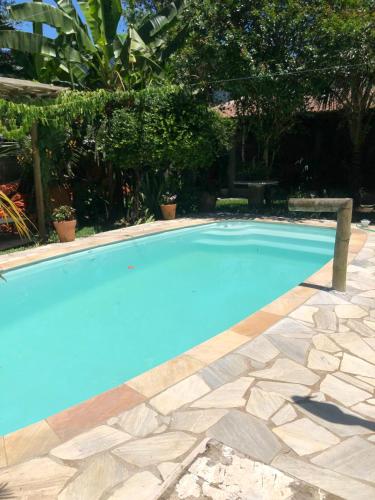 a large blue swimming pool with a stone patio at Suíte Recanto bom Sossego in Ubatuba