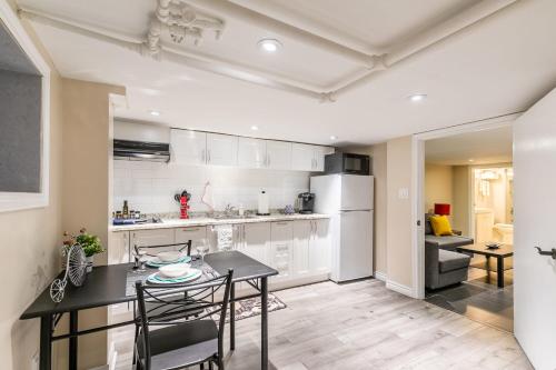 a kitchen with white cabinets and a table and chairs at Modern Suite Condo Heart Of St Clair West - Bloor Hotel in Toronto