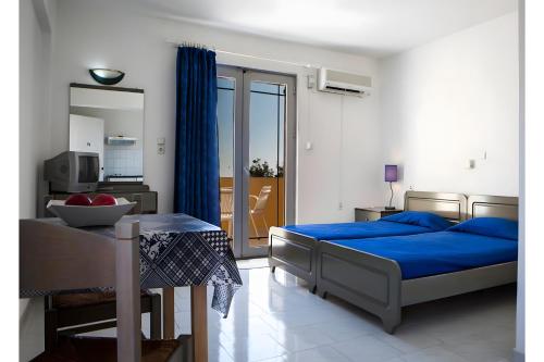 una camera da letto con un letto con lenzuola blu e un tavolo di Pegasus Studios a Karavádhos
