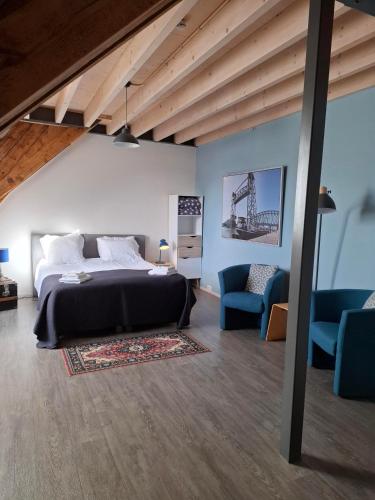 ein Schlafzimmer mit einem Bett und zwei blauen Stühlen in der Unterkunft De Gaanderij bed and Breakfast in Barendrecht