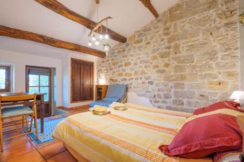 1 Schlafzimmer mit Steinwänden, einem Bett und einem Tisch in der Unterkunft Chambre La Louve in Berrias Et Casteljau