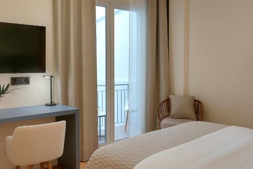 a bedroom with a bed and a desk with a television at Elite Patras Suites in Patra
