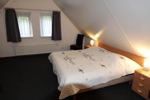 een slaapkamer met een bed, een stoel en ramen bij Bungalow Het Uilennest | 6 personen - Vakantiepark De Kremmer in Gasselte