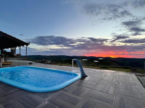 Uma banheira de hidromassagem azul em um pátio ao pôr do sol. em Solar Serra das Piteiras - Paivas - Pará de Minas, Minas Gerais em Pará de Minas