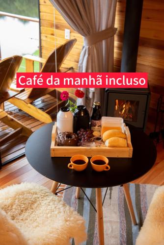 ein Tablett mit Speisen auf einem Tisch und einem Kamin in der Unterkunft Cabana Água - Cabanas Recanto do Lago in Nova Petrópolis