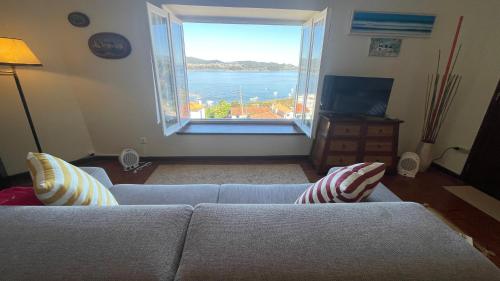 a living room with a couch and a large window at CASA da LINHA in Caminha