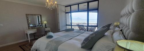 a bedroom with a large bed with a large window at Bloubergstrand Beachfront Apartment Witsand 101 Tablemountain and ocean views in Cape Town