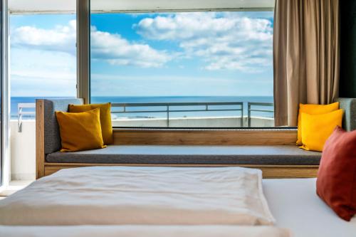 a bedroom with a large window with a view of the ocean at Ostseehotel Midgard in Damp in Damp