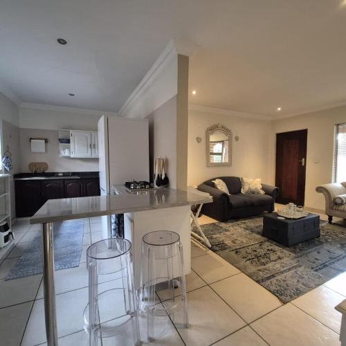 eine Küche und ein Wohnzimmer mit Tisch und Stühlen in der Unterkunft Luxurious 2-Bedroom French Cottage with parking in Roodepoort