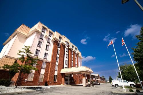 a large brick building with a white car parked in front of it at Waterloo Suites Hotel, Trademark Collection by Wyndham in Waterloo