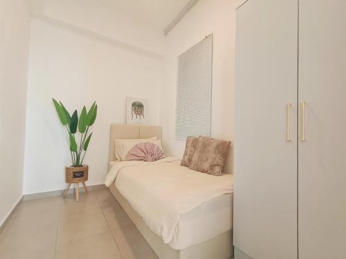 a white bedroom with a bed and a potted plant at KLIA Airport Xiamen Sepang WiFi Gym Pool 吉隆坡国际机场 厦门大学 in Kampong Bekoh