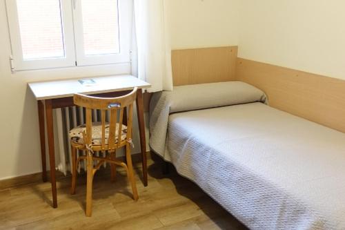 a room with two beds and a desk and a chair at Alojamiento cristo rey in Pozuelo de Alarcón