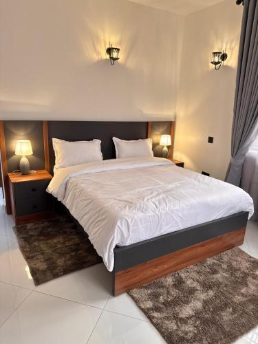 una camera da letto con un grande letto con due comodini e due lampade di Jacob's Courts Apartment 6 a Kampala