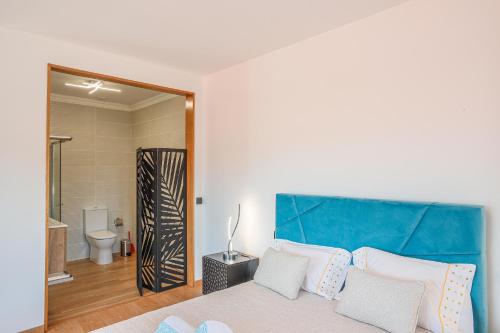 a bedroom with a bed with a blue headboard and a bathroom at Mirando Espanha in Melgaço