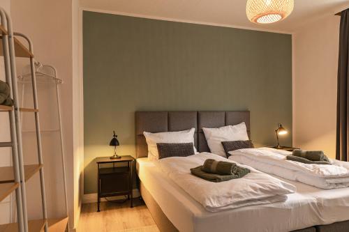 a bedroom with two beds and a green wall at HeideHygge 2 in Schneverdingen
