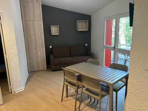 un salon avec une table, des chaises et un canapé dans l'établissement VVF Aveyron Najac, à Najac